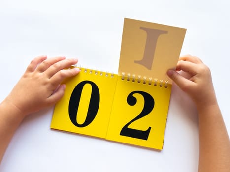 Childs hands flipping educational flashcards with numbers and letters on bright yellow background.