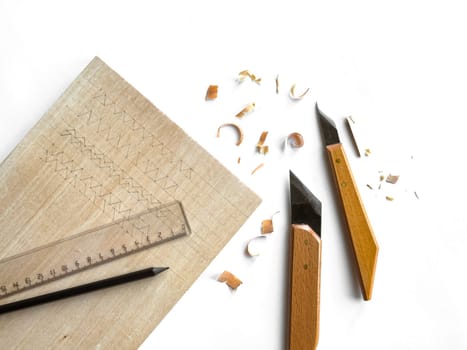 Wood carving tools and shavings on white background.