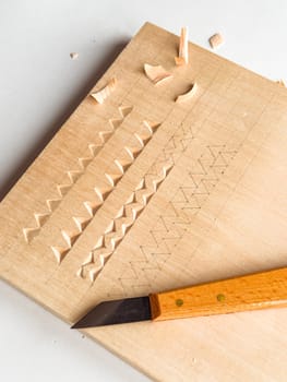 Wood carving techniques on softwood with precision knife and geometric patterns.