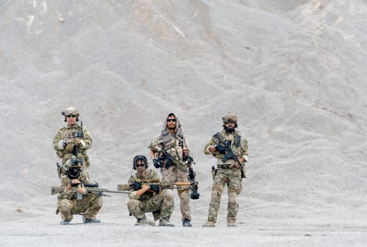 Group of military or soldier with hold different types of weapon or gun stay with relax position in front of limestone mountain of outdoor practice area.