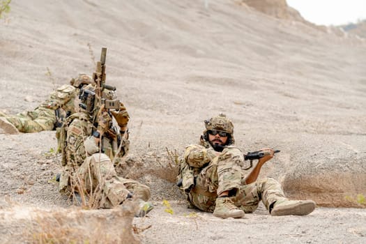 Two of military or soldiers with hold the gun stay low with lie and sit near the moutain during practice for fighting outdoor.