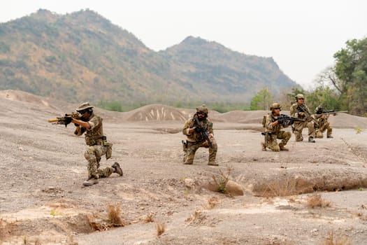 Wide shot of group of military or soldiers sit in the line formation and stay in ready status to fight with enemy outdoor.