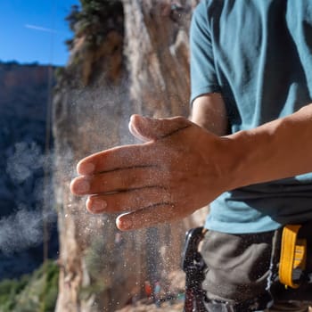 Male hands with magnesia powder close-up against the background of the mountains on a sunny day, the hands of a climber who prepares for outdoor training, a man is engaged in active sports in Greece.