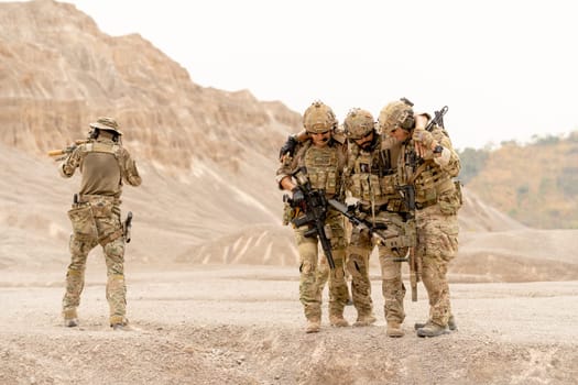Group of military or soldier support or bear member of his team to escape from danger and protect by the other one point gun to the back, in area of practice or outdoor battlefield.