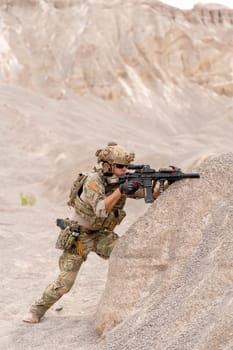 Vertical image of military or soldier with hold gun and stand in postition fighting in battlefield with near the mountain during outdoor practice.