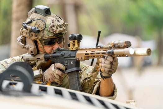 Military or soldier stay in front of humvee car area of car hood and point gun to right side during outdoor practice.