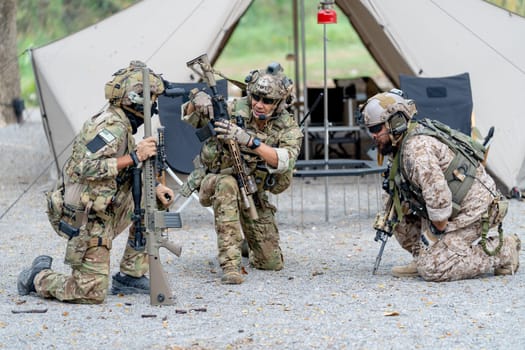 Group of militaries or soldiers discuss and stay in front of tent during outdoor practice.