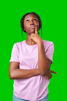 Thoughtful woman pondering in front of a bright green background during a casual moment close up