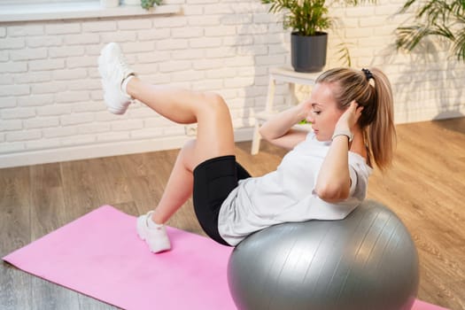 Young woman exercising on a stability ball in a bright room with plants close up