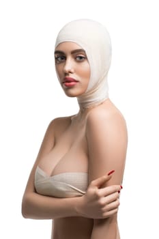 Girl her head, neck and breasts bandaged at plastic surgeon isolated shot on white background