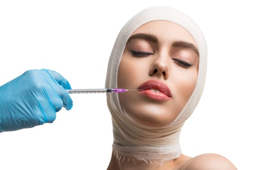 Girl her head and neck bandaged getting beauty lips injection at plastic surgeon isolated shot on white background