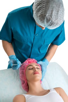 Plastic surgeon making beauty injections to his patient lying on a coach high angle shot