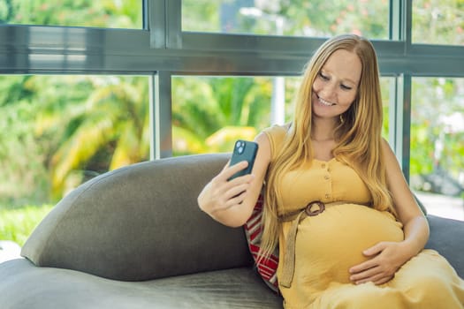 Beautiful woman holding pregnant belly and using phone, calling friends or family via video call.
