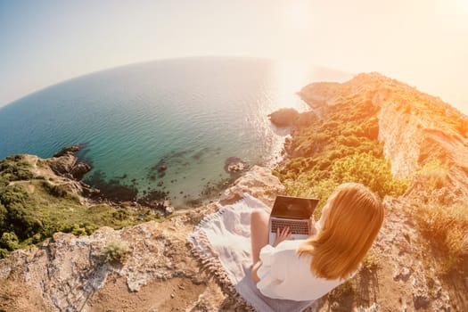 Woman sea laptop. Business woman in yellow hat working on laptop by sea. Close up on hands of pretty lady typing on computer outdoors summer day. Freelance, digital nomad, travel and holidays concept.