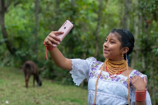 sweet girl in the jungle of ecuador, with a sincere smile and ancestral dress taking a selfie with a smartphone and in the background a llama from her farm. High quality photo