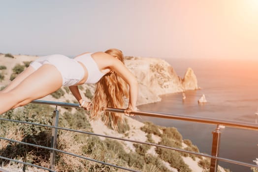 Fitness woman sea. Outdoor workout on yoga mat in park near to ocean beach. Female fitness pilates yoga routine concept. Healthy lifestyle. Happy fit woman exercising with rubber band in park.