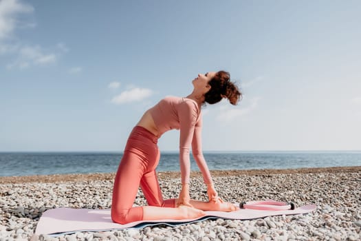 Middle aged well looking woman with black hair doing Pilates with the ring on the yoga mat near the sea on the pebble beach. Female fitness yoga concept. Healthy lifestyle, harmony and meditation.