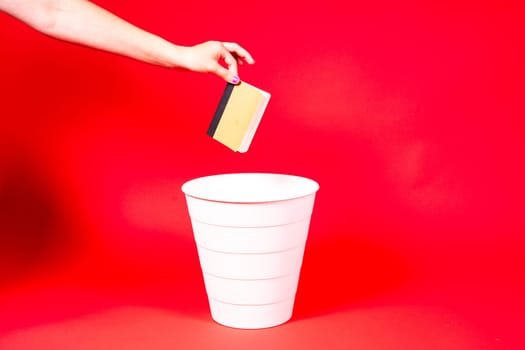 Throw notepad, notebook or diary into trash bin, notepad in a hand in front of trash can