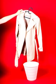 Shot of young woman hand throwing her outwear dress in the trash isolated on red background