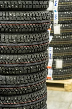 Sale of car tires for sale in the store. Many new winter tires lie horizontally. There is space for text