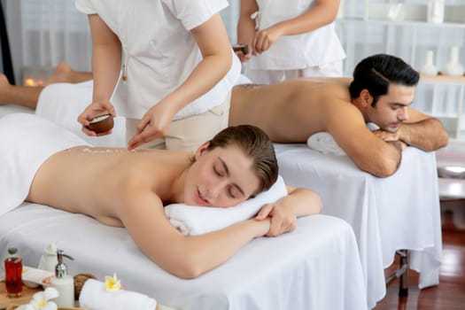 Woman customer having exfoliation treatment in luxury spa salon with warmth candle light ambient. Salt scrub beauty treatment in health spa body scrub. Quiescent