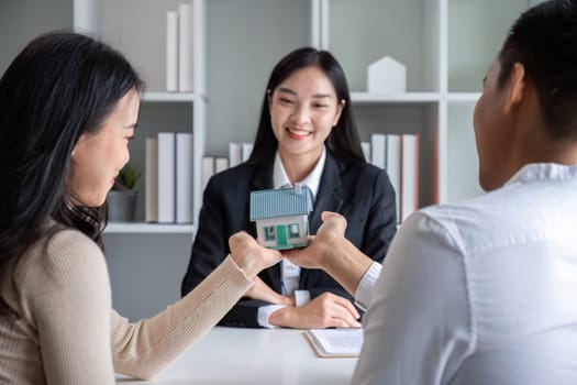 The real estate agent makes an offer to get the couple to sign a contract to buy the house. Happy male and female married customers make intimate deals with agents. real estate concept..