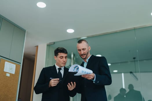 Two business men meeting to talking or discuss marketing work in workplace using paperwork, calculator, computer to work