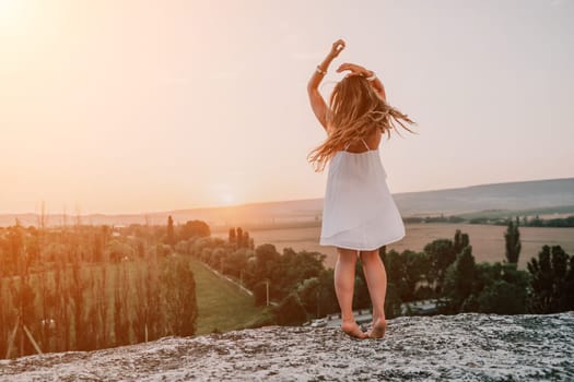 Romantic beautiful bride in white dress posing with sea and mountains in background. Stylish bride standing back on beautiful landscape of sea and mountains on sunset