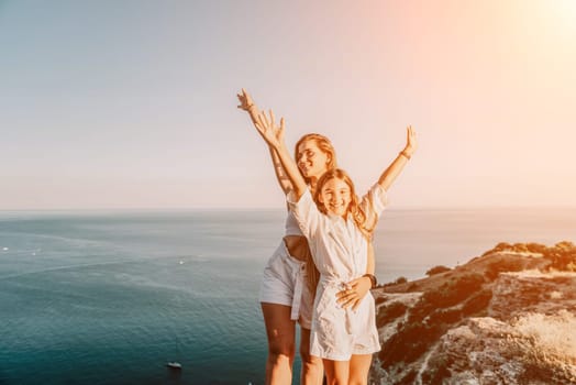 Close up portrait of mom and her teenage daughter hugging and smiling together over sunset sea view. Beautiful woman relaxing with her child.