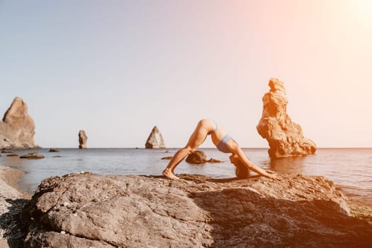 Middle aged well looking woman with black hair doing Pilates with the ring on the yoga mat near the sea on the pebble beach. Female fitness yoga concept. Healthy lifestyle, harmony and meditation.