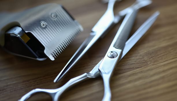 Close-up of hairdresser professional instrument. Metal tools laying on wooden table. Job profession to take care of persons hair. Scissors for cutting and thinning out hair