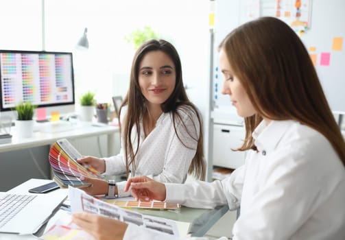 Portrait of smart businesswoman sitting at modern workplace with high-tech computers with multicolored palettes on screen. People discussing project. Creative office concept