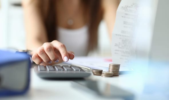 Focus on tender hands of witty businesswoman sitting indoors and using calculator for counting in important tablet with charts. Office concept. Blurred background