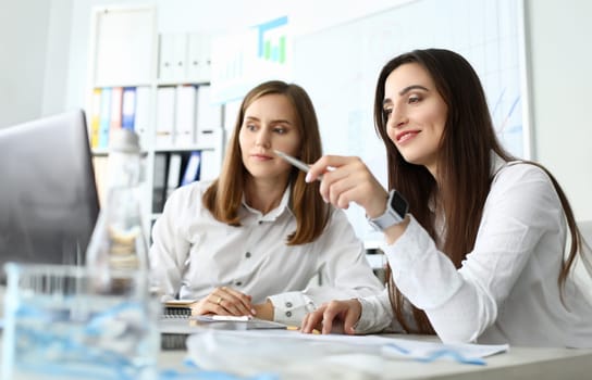 Portrait of smart businesswoman sitting at comfortable workplace and holding metallic writing pen with concentration and satisfaction. Accounting office concept