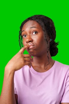 Thoughtful woman pondering in front of a bright green background during a casual moment close up