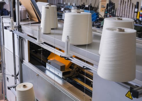 Big spools with white thread for rewinding at knitting shop view