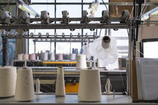 Big spools with white thread at rewinding machine view