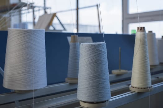Big spools with white thread for rewinding at knitting shop view