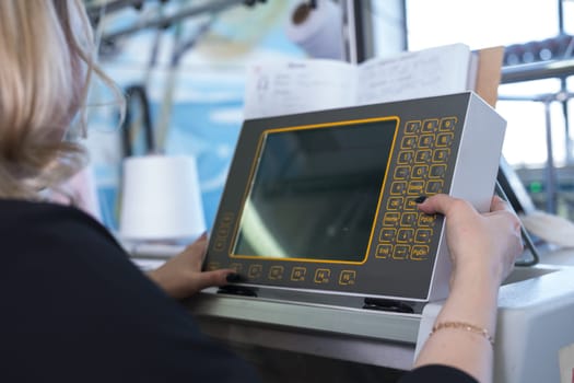 Female operator setting programme at knitting machine control panel view