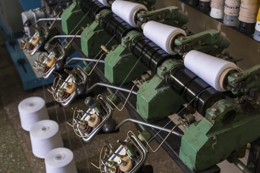 Big white thread spools at rewinding machine at knitting shop view
