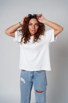 Surprised woman expressing strong emotions with wide eyes and raised hands, studio setting close up