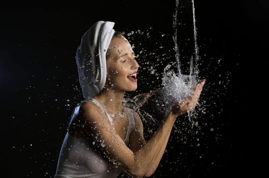 Happy girl washing her face isolated cropped shot on black background