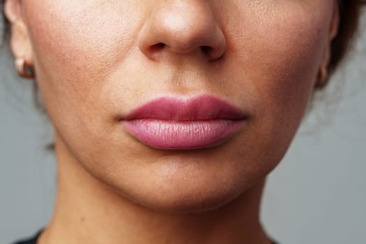 Close-up of a woman showcasing her natural skin texture and subtle lip color in soft lighting