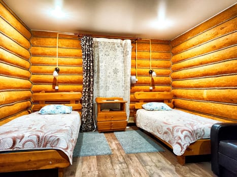 The cabin showcases a warm wooden interior with two neatly made single beds and soft textiles, creating a tranquil accommodation space.