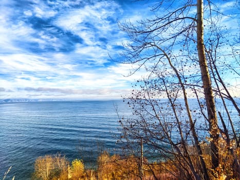 The calm waters of Baikal Lake reflect the sky while autumn trees frame the peaceful landscape, inviting relaxation and reflection.