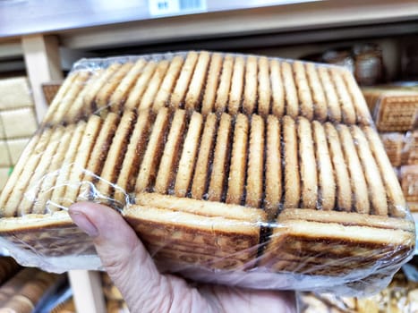 A person selects a bag of delicious cookies while shopping at a local store. Difficult balancing treats with a healthy lifestyle choice
