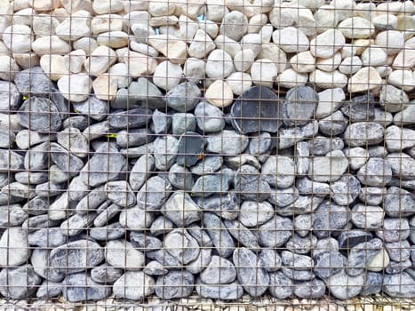 A stone wall features a mix of gray and white pebbles neatly arranged for decorative purposes.