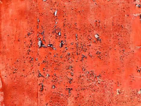 A vibrant red wall shows signs of wear, featuring peeling paint and an uneven texture, perfect for adding character to any design.