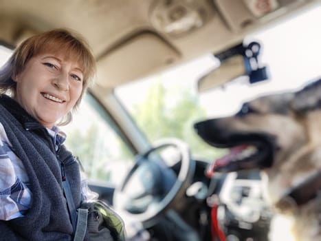 A cheerful woman smiles while seated in a car, enjoying quality time with her dog beside her on a bright, sunny day.
