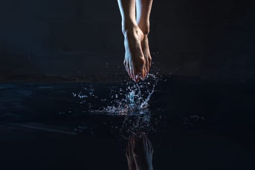 Woman jumping in water barefoot cropped shot in dark room